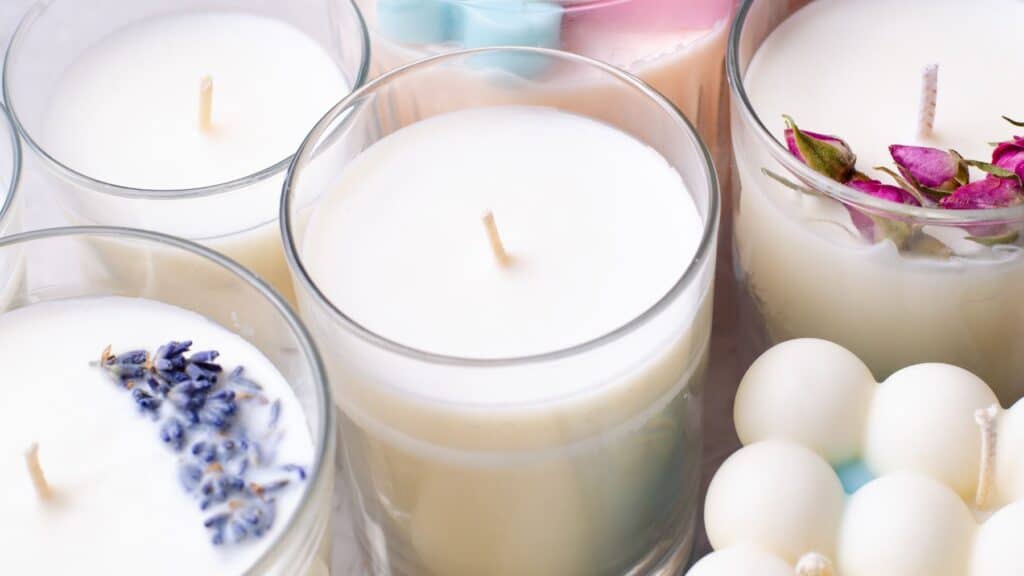 Assorted scented candles with natural decorations.