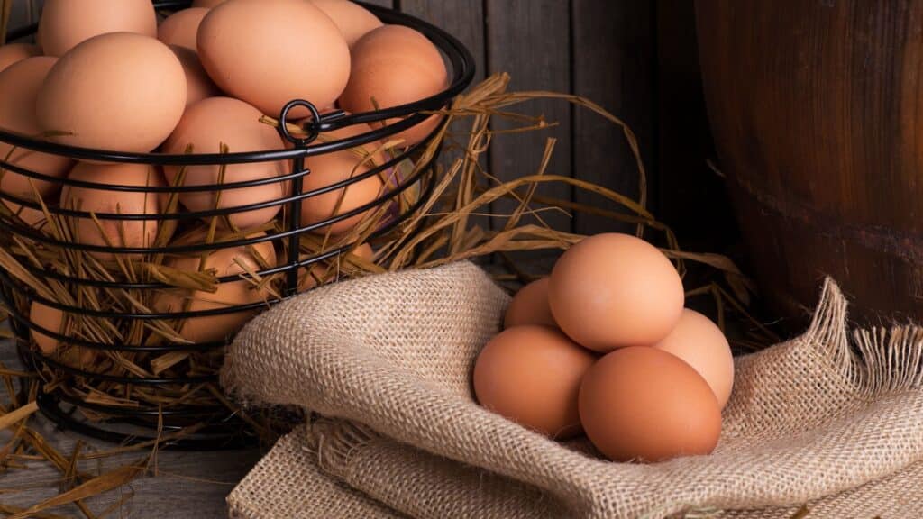 Brown eggs in basket with straw and burlap.