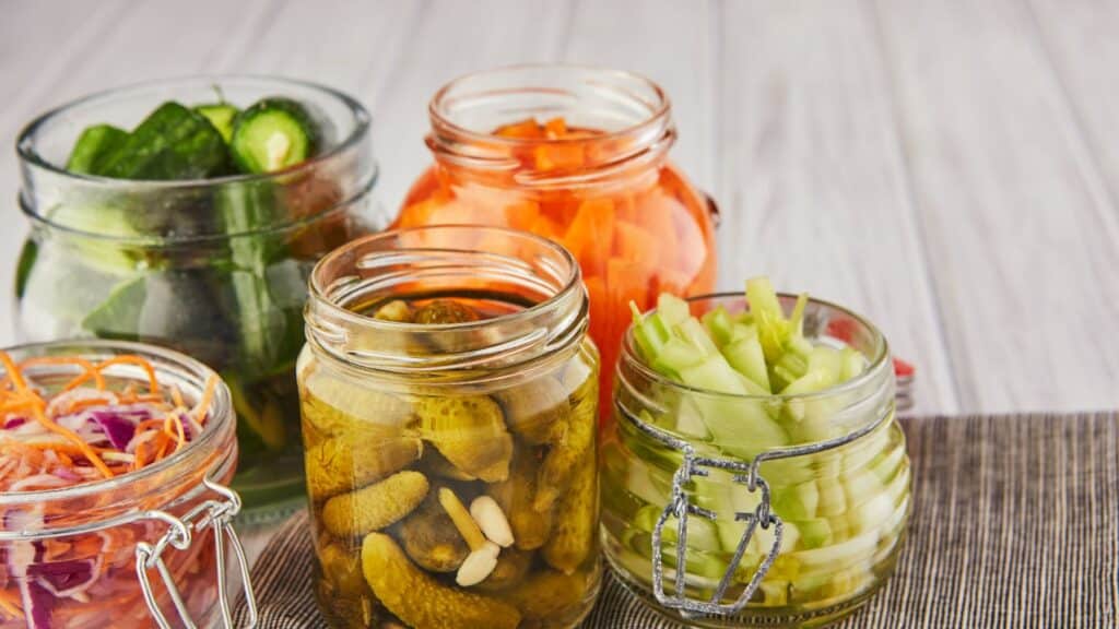 Assorted fresh pickled vegetables in glass jars.