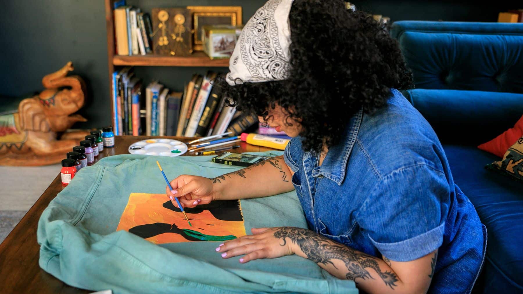 Artist painting on denim jacket at home.